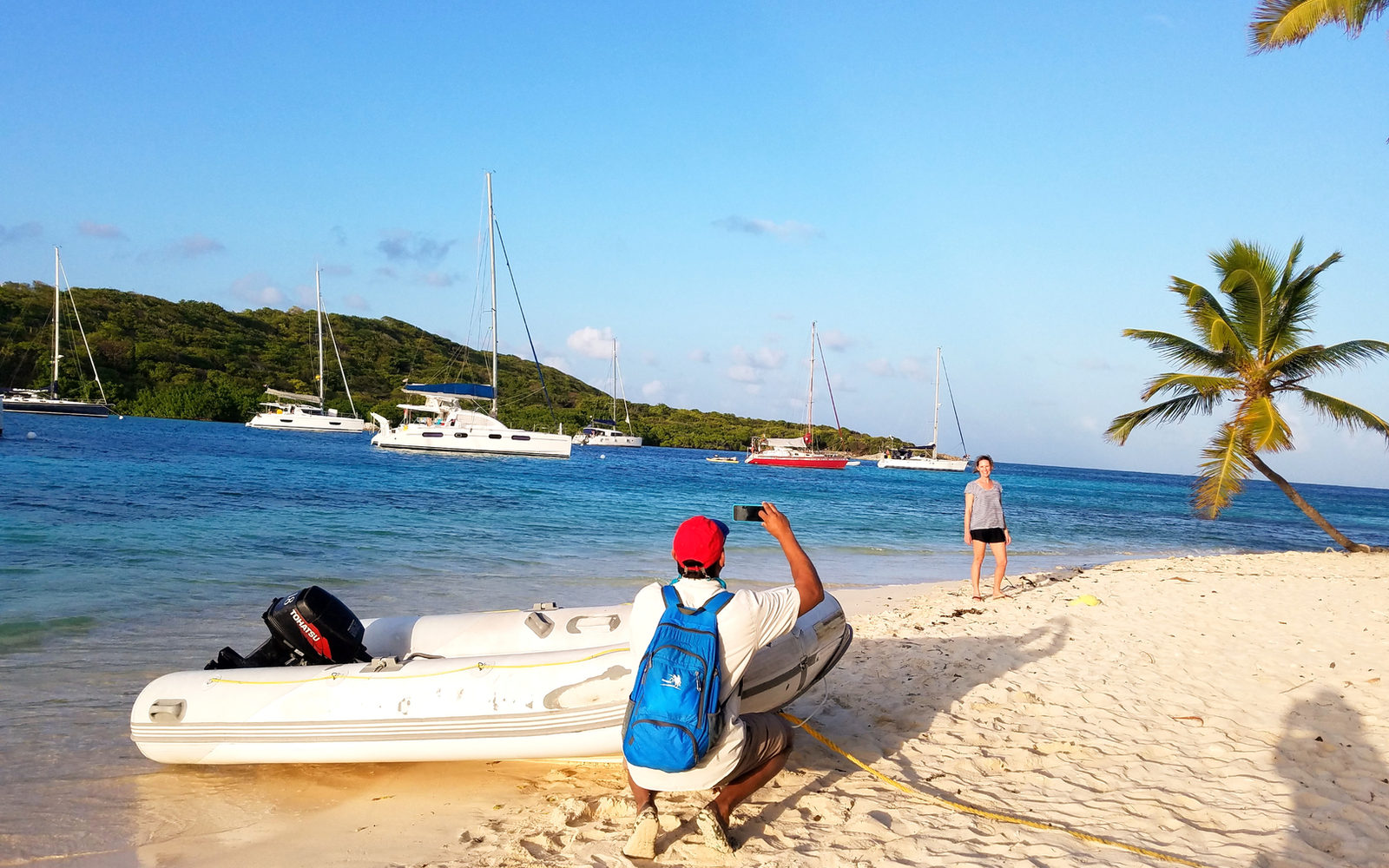 Beach in the British Virgin Islands with a dinghy and sailboats offshore